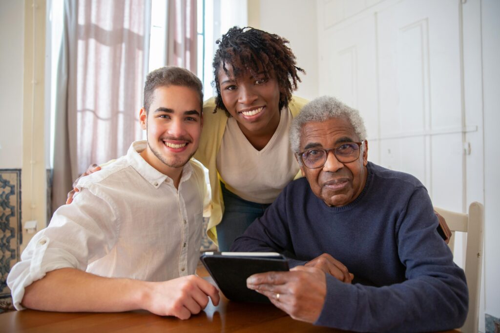 pexels-photo-7551617-7551617 Elderly man enjoying technology with diverse caregivers at home.